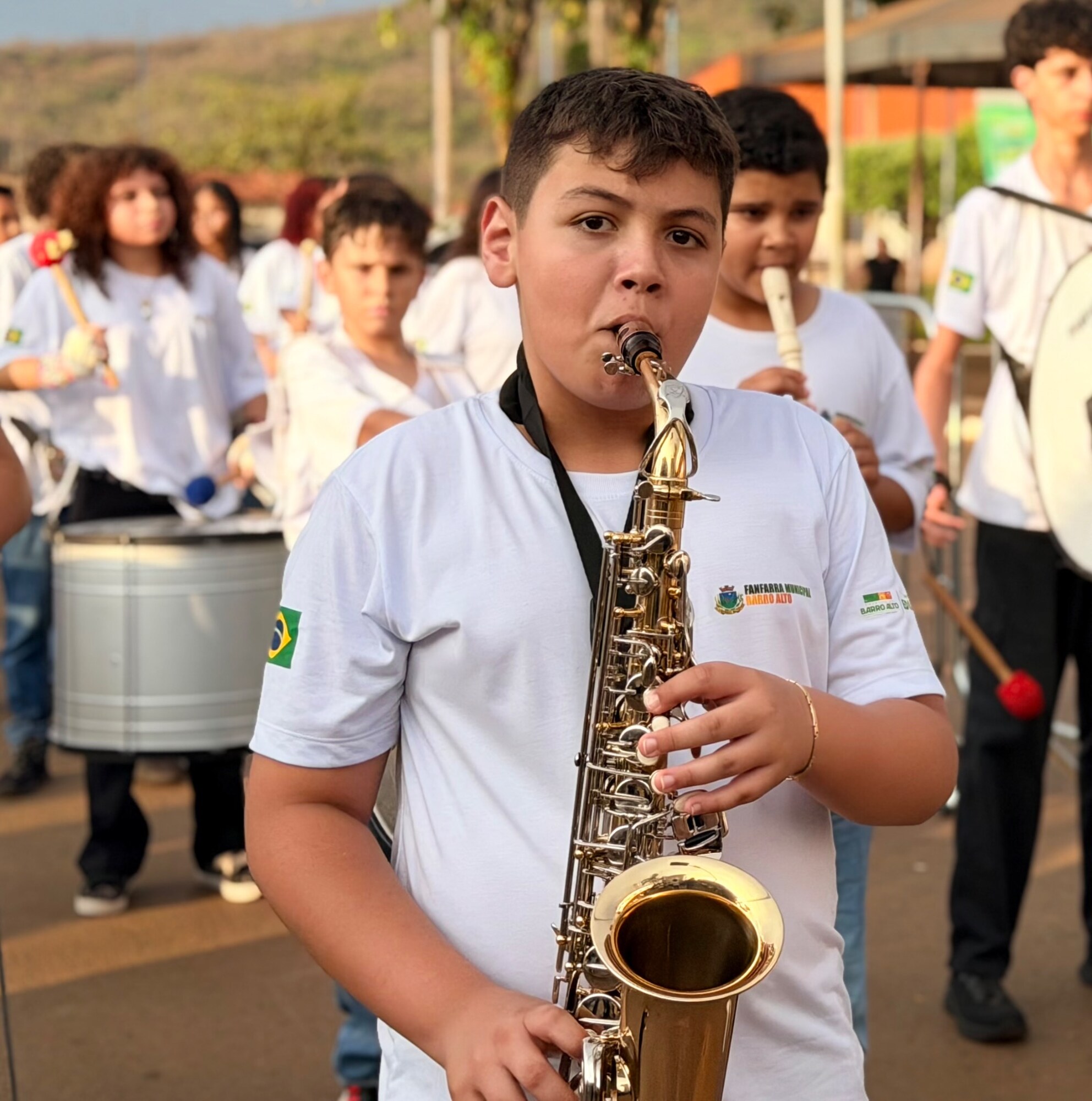 Aluno saxofonista à frente da fanfarra do Projeto Música na Escola